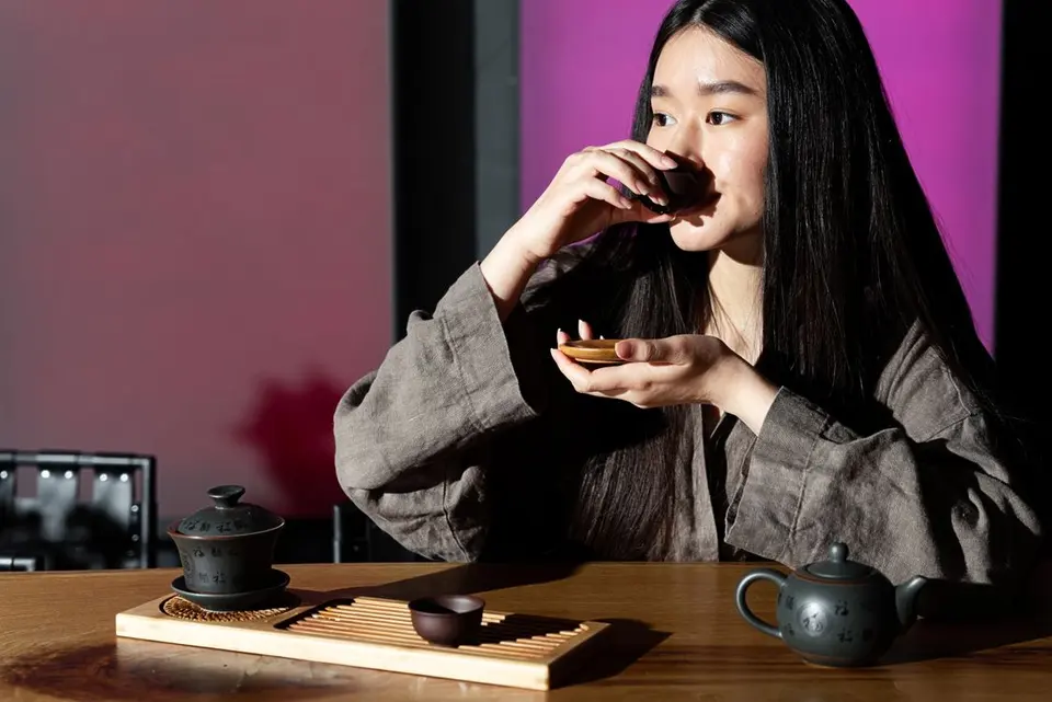 传统茶席上，一位女性正在品饮茶汤